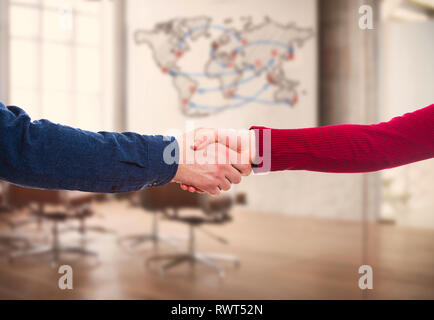 L uomo e la donna di handshake ufficio su sfondo al coperto con mappa del mondo. Attività di partenariato e di collaborazione tra i diversi paesi. Il commercio globale Foto Stock
