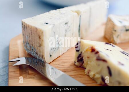 Vista ravvicinata di una scheda di formaggio con un coltello per formaggio servita su una tavola di legno Foto Stock