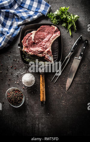 Costata di manzo in padella per grigliare con erbe aromatiche sale pepe coltello e forchetta. Foto Stock