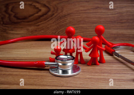 Lo stetoscopio e la famiglia la bambola con il cuore. Concetto di salute. Foto Stock