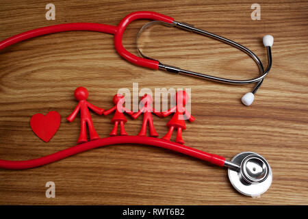 Lo stetoscopio e la famiglia la bambola con il cuore. Concetto di salute. Foto Stock
