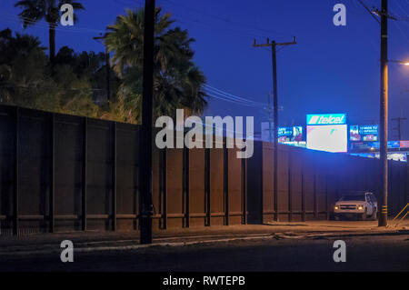 Recinzione di confine nel centro cittadino di Calexico California, in prima serata, appena ad est del centro cittadino di porto di entrata, recinto è relativamente breve e quindi facilmente scalato. Foto Stock