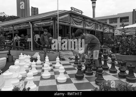 Mar Gen 1° 2019,Auckland Nuova Zelanda - due ragazzi adolescenti giocare una partita a scacchi su una grande scacchiera esterna con grandi pezzi di scacchi. Foto Stock