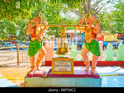 BAGO, MYANMAR - 15 febbraio 2018: due statue maschili con grande campana buddista in ombra del giardino di Shwe Gu Pagoda di laici, su 15 Febbraio a Bago. Foto Stock