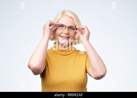 Sorridente attraente senior imprenditrice indossando occhiali colpo di testa, felice di età insegnante, vecchio Esecutivo femmina. Controllare la vista. Foto Stock