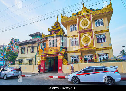 YANGON, MYANMAR - 15 febbraio 2018: la facciata ornata di Damikar Yarma monastero intagliato con decorazioni dorate e multitired pyatthat tetto, nel febbraio Foto Stock