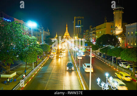 Traffico di sera lungo sule strada, situato nel centro cittadino, il gigante golden Sule Pagoda è visto sullo sfondo, Yangon, Myanmar. Foto Stock