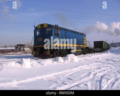 freight locomotive train rides on the rails of the industrial railway in the winter Foto Stock