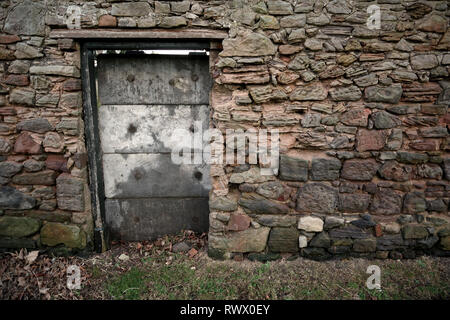 Un Creepy Porta Vecchia in un antico muro di pietra. Foto Stock