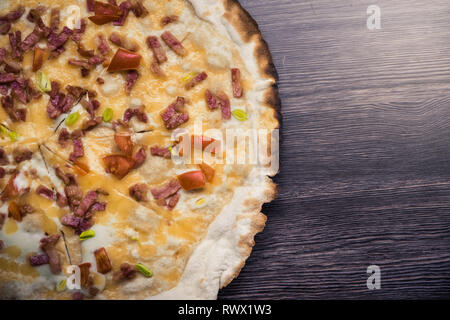 Pizza artigianale contro il legno scuro dello sfondo. Spazio di copia la pizza. Fatte a mano Foto Stock