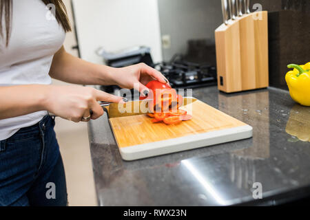 Felice giovane donna il taglio di verdure fresche in cucina Foto Stock