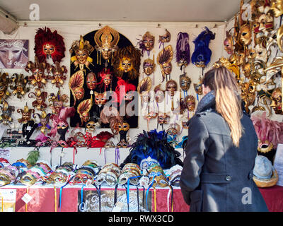 Venezia, Italia - Marzo 2, 2019 Tourist navigare in diversi modelli di maschera in un mercato di strada stand durante il Carnevale di Venezia Foto Stock