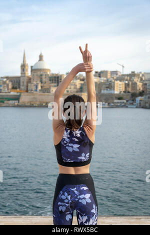 Donna in piedi di fronte a La Valletta, Malta, con le braccia aperte, libertà di viaggio. Foto Stock