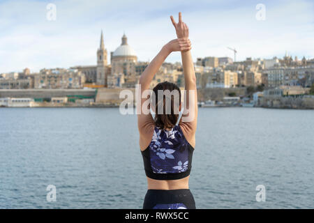 Donna in piedi di fronte a La Valletta, Malta, con le braccia aperte, libertà di viaggio. Foto Stock