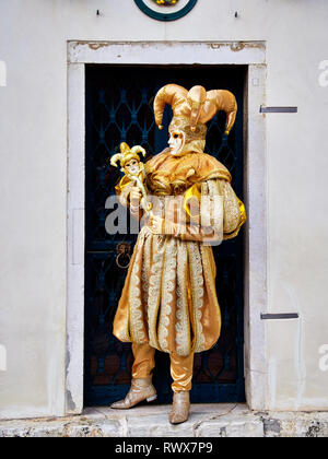 Venezia, Italia - Marzo 1, 2019 Una persona vestita con un oro costume di Arlecchino Venezia durante le feste di Carnevale Foto Stock