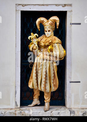 Venezia, Italia - Marzo 1, 2019 Una persona vestita con un oro costume di Arlecchino Venezia durante le feste di Carnevale Foto Stock