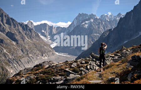 Un solitario escursionista femmina si affaccia su un ghiacciaio valle nella regione di Chamonix nelle alpi della Francia. Foto Stock