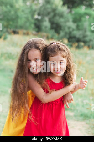 Ritratto di due simpatici bambine abbracciando e ridere per la campagna. Contenti i bambini all'aperto Foto Stock