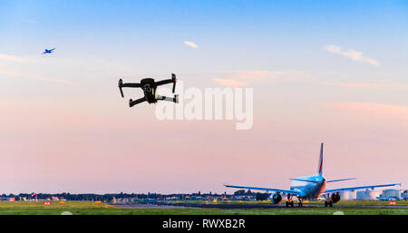 Drone senza pilota battenti vicino alla pista di atterraggio all'aeroporto mentre aereo commerciale decolla portando ad una possibile collisione - digital composite. Foto Stock