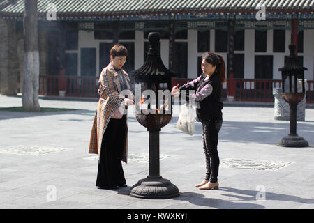 XI'an, Cina - 9 ottobre 2018: due donne cinesi bruciare bastoncini di incenso in un tempio taoista Ba Xian un nella citta' di Xian, Cina. Foto Stock