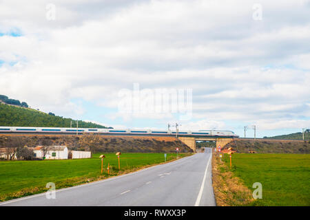 Ad alta velocità AVE di treno che viaggia lungo un ponte al di sopra della strada. Fuente El Fresno, Ciudad Real Provincia, Castilla La Mancha, in Spagna. Foto Stock