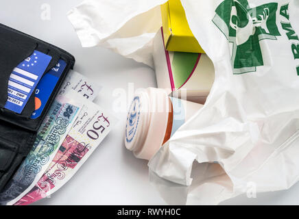 Tessera di assicurazione sanitaria europea in un portafoglio lungo con parecchie sterline e medicinali in un sacchetto, concetto di medico di aumentare nella crisi del Foto Stock