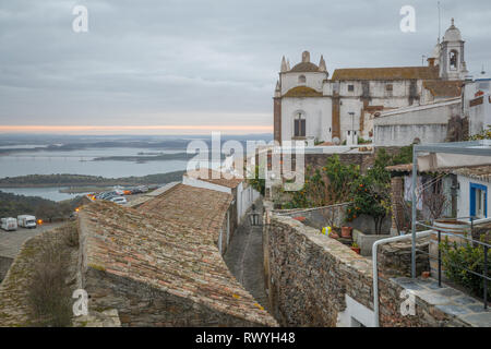 Vista al tramonto sul borgo, Nostra Signora della laguna chiesa e Lago di Alqueva, Monsaraz, Portogallo Foto Stock