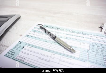 Noi sotto forma di imposta accanto alla calcolatrice e forma fiscale 1040. tasse ci costituiscono redditi di impresa office a mano il concetto di riempimento Foto Stock