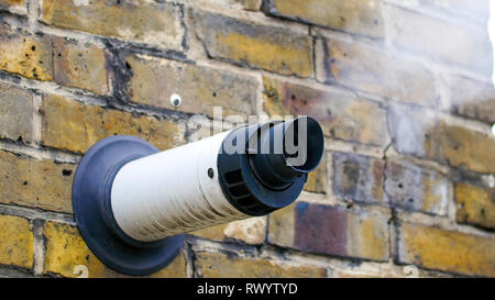 Un vapore che fuoriesce da una ventilazione in una parete. Il fumo bianco che esce dal vapore può proviene dall'edificio all'interno Foto Stock