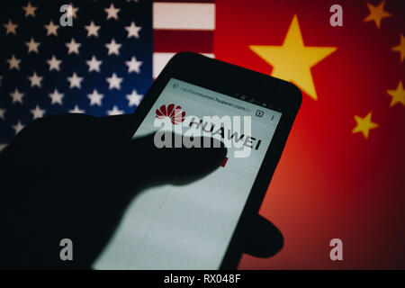 Huawei logo sul suo sito web è mostrato su un display dello smartphone, Stati Uniti bandiera e la Repubblica popolare di Cina bandiera non focalizzato sullo sfondo Foto Stock
