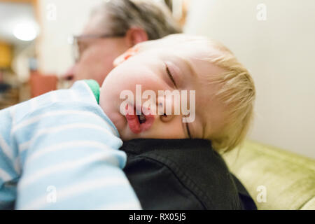 Close-up del nonno che trasportano carino nipote dorme sulla spalla a casa Foto Stock