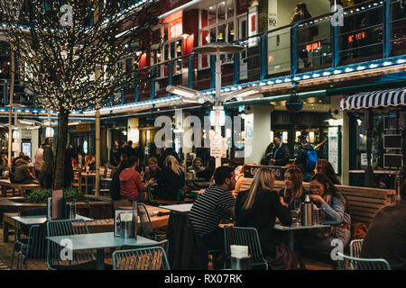 London, Regno Unito - 6 Marzo 2019: persone sedute a tavoli esterni della corte regale, un edificio a tre piani alimentari alfresco e sala da pranzo cortile nel cuore di Lo Foto Stock