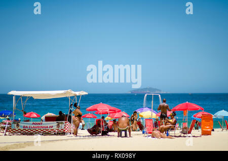 RIO DE JANEIRO - Febbraio 10, 2017: Beachgoers prendere nel mezzogiorno sole estivo in un colorato barrack (spiaggia tenda) a Leme, alla spiaggia di Copacabana. Foto Stock