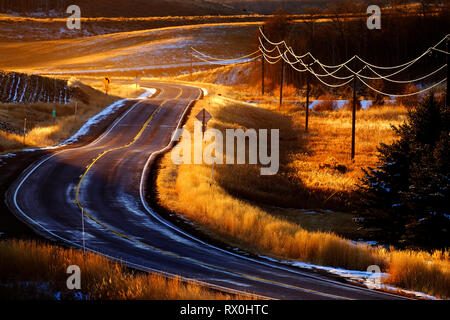 Vecchia strada di campagna con le spire e le curve i cavi telefonici incandescente nella luce del sole dorato Foto Stock