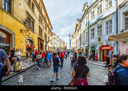 I turisti affollano il Re della strada attraverso la strana maschio godendo di negozi e caffetterie sulla strada per il Castello di Praga complesso con la chiesa di San Nicola in vista Foto Stock