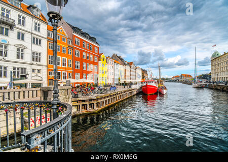 I turisti passeggiata, guida scheda barche e cenare presso caffetterie lungo la strada in una giornata autunnale del xvii secolo waterfront canal Nyhavn a Copenaghen, in Danimarca. Foto Stock