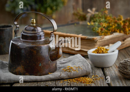 Teiera vintage, malta di sano erbe medicinali, vecchio libro e Hypericum - St Johns wort mazzetto. Foto Stock