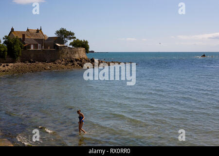 Cottage e la cappella e dal mare, con una signora la balneazione a bassa marea, Saint-Vaast-la-Hougue, Normandia, Francia Foto Stock