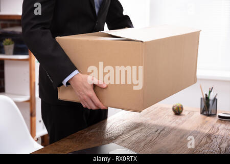 Imprenditore che porta le sue cose in una scatola di cartone al lavoro Foto Stock