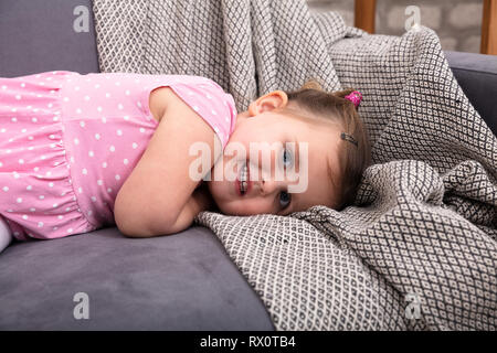 Sorridente Bambina sdraiato sul divano di casa Foto Stock