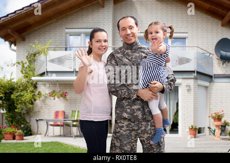 Close-up di un soldato felice riunita con la famiglia al di fuori della loro casa Foto Stock