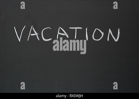 Vacanza scritto a mano in gesso su una lavagna Foto Stock