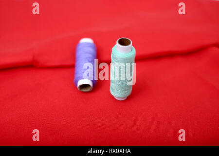 Immagine del filo di cucitura sul panno rosso. Foto Stock