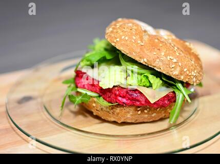 Primo piano della barbabietola burger con grigliate di foglie di rucola sul piatto di legno. Foto Stock