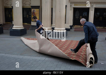 Tappeto installatori srotolare un tappeto di nuovo in strada per la parte interna del Lyceum Theatre sul Wellington Street, il 5 marzo 2019, a Londra, in Inghilterra. Foto Stock