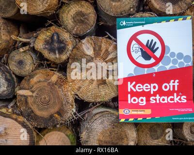 Un mucchio di tagliare legname segato connesso ad albero abbattuto alberi timber log registra di condire con il cartello di avviso per il settore forestale Foto Stock