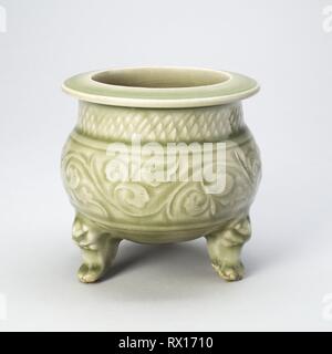 Treppiede Incensiere (incensiere) con Peony-Leaf Scrolls, petali di reticolare e Masklike gambe. Cina. Data: 1100-1199. Dimensioni: H. 11.0 cm (4 3/8 poll.); diam. 10,7 cm (5 1/4 in.). Yaozhou ware; porcellanato con underglaze intagliato e decorazione plastica. Provenienza: Cina. Museo: Chicago Art Institute. Foto Stock