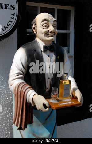 Modello a grandezza dell uomo, vestito come cameriere, in piedi fuori casa pubblica tenendo il vassoio con bottiglia di whisky e vetro, Inveraray, Scozia Foto Stock