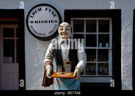 Modello a grandezza dell uomo, vestito come cameriere, in piedi fuori casa pubblica tenendo il vassoio con bottiglia di whisky e vetro, Inveraray, Scozia Foto Stock