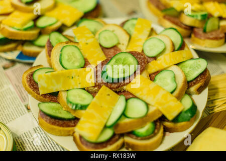 Panini con salsiccia e formaggio e cetrioli su una piastra. Foto Stock